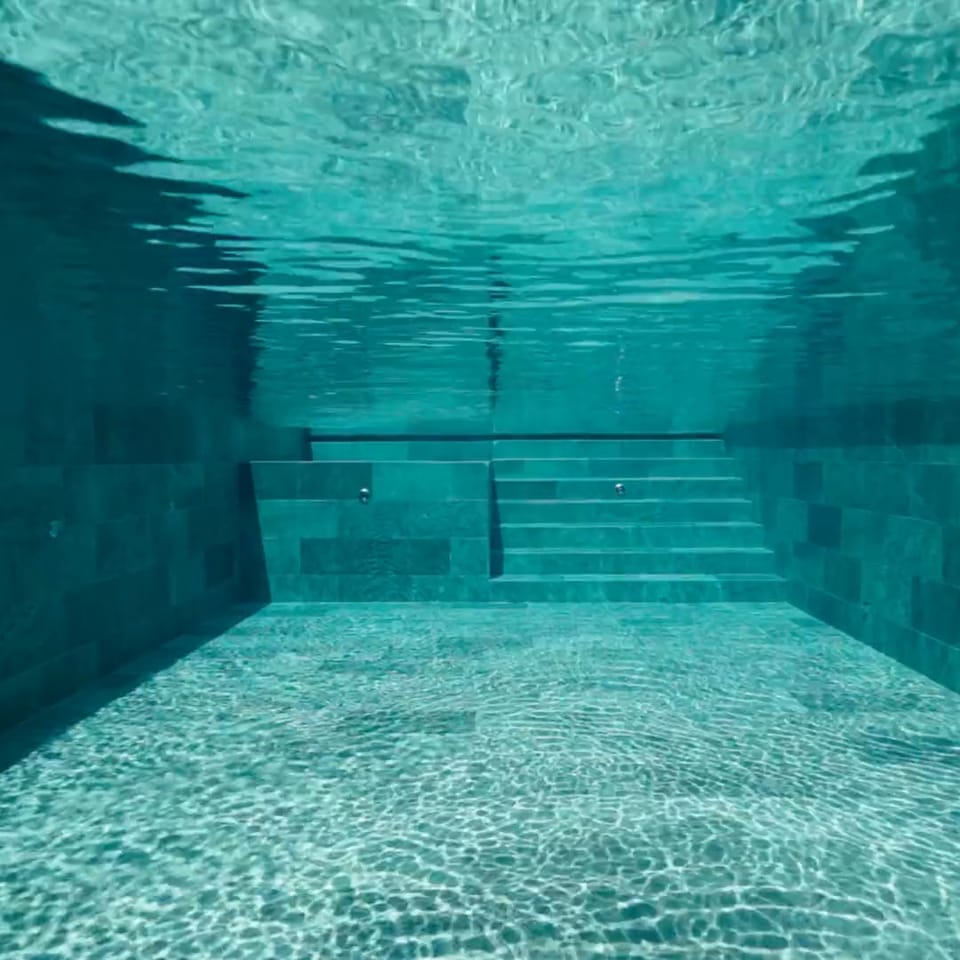 Underwater view of the turquoise tiled pool interior and steps